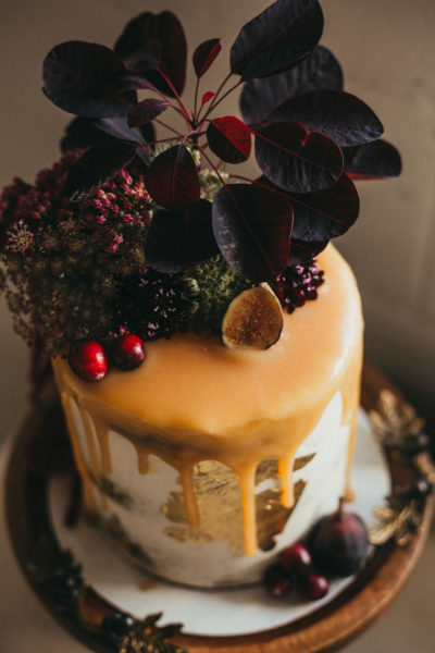 Organic cake with dripping icing with fresh flowers and fruit