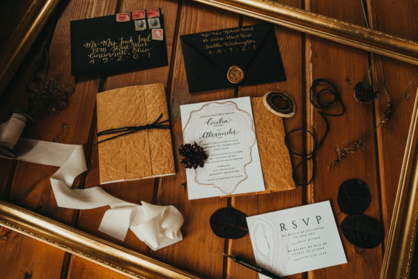 black and gold hand lettered invitation suite laying on a rustic wood table, It's all in the Details